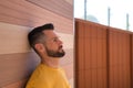 Portrait of handsome young man, with blue eyes and yellow shirt, with his head leaning against a wall very worried. Concept beauty Royalty Free Stock Photo