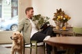 Portrait of handsome young man, cafe visitor, sitting with his dog, petting golden retriever and reading news on digital Royalty Free Stock Photo