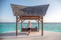 Portrait of handsome young man in expensive shirt standing  near the swing and water villas at the tropical island luxury resort Royalty Free Stock Photo