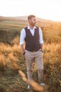 Portrait of handsome young man, farmer or cowboy, wearing casual suit, looking to a side, while standing in summer field Royalty Free Stock Photo