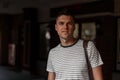 Portrait of a handsome young man with gray eyes with a stylish haircut in a fashionable striped T-shirt with a leather bag Royalty Free Stock Photo