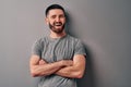 Portrait of a handsome young man leaning against a gray wall crossed his arms and winks and smiles Royalty Free Stock Photo