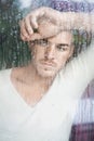 Portrait of handsome young man looking through wet windo Royalty Free Stock Photo