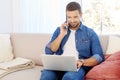 Young man using mobile phone and notebook while sitting on couch at home Royalty Free Stock Photo