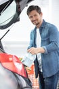 portrait handsome young man packing groceries into car trunk Royalty Free Stock Photo