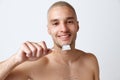 Portrait of handsome young man with perfect white teeth posing shirtless with toothbrush and paste against white studio Royalty Free Stock Photo