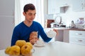 Portrait of handsome young man pours tea with cat on the kitchen