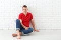 Portrait of handsome young man sitting near white brick wall Royalty Free Stock Photo