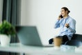 Portrait of handsome young man sitting at office desk with laptop computer and talking on mobile phone. Communication concept Royalty Free Stock Photo