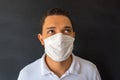 Portrait of a handsome young man with a surgical medical mask on a white shirt, standing up. Indoor studio shot, isolated on a Royalty Free Stock Photo