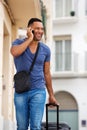 Handsome young man talking on mobile phone with bag Royalty Free Stock Photo