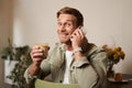 Portrait of handsome young man talking on the phone, sitting in cafe and drinking coffee, answering a call Royalty Free Stock Photo