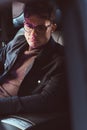 A handsome young man wearing glasses sitting in the back seat of the car. Royalty Free Stock Photo