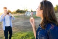 Handsome young man taking photo of his girlfriend making soap bubbles in the park. Royalty Free Stock Photo