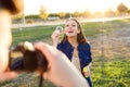 Handsome young man taking photo of his girlfriend making soap bubbles in the park. Royalty Free Stock Photo