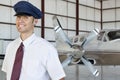 Portrait of handsome young pilot standing in front of airplane Royalty Free Stock Photo