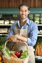 Portrait of handsome young salesperson standing with basket full of vegetables