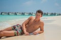 Portrait of handsome young tanned man resting at the beach at the tropical island luxury resort Royalty Free Stock Photo