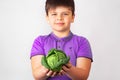 Portrait of handsome young teen boy holding fresh green cabbage and looking at camera, isolated on white background Royalty Free Stock Photo