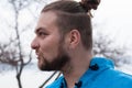 Portrait of hansome bearded man with hair bun and make up looking away and speaking