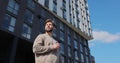 Portrait of hansome young caucasian man holding paper cup in hand at modern buildings in the background. Royalty Free Stock Photo