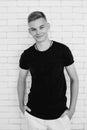 Portrait of hansome young man teen in black t-shirt and white pants on white bricks