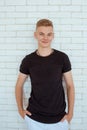 Portrait of hansome young man teen in black t-shirt and white pants on white bricks