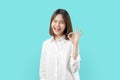 Portrait happily Asian woman shows ok sign and braces smiling witch looking at the camera on blue background.
