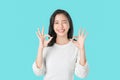 Portrait happily Asian woman shows ok sign and smiling witch looking at the camera on blue background.