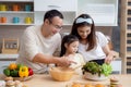 Portrait happiness asian family with father and mother and daughter preparing cooking salad vegetable food together in kitchen. Royalty Free Stock Photo