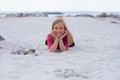 Portrait happy adorable little girl in neoprene swimsuits laying on the beach on white sand on sea Royalty Free Stock Photo