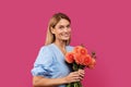 Portrait of happy adult caucasian female blonde in dress with bouquet of flowers looks at camera Royalty Free Stock Photo