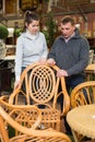 Couple choosing wicker armchair in store