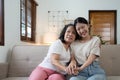 Portrait happy adult daughter and older mother hugging and holding hands, sitting on couch at home, young woman and Royalty Free Stock Photo