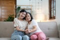 Portrait happy adult daughter and older mother hugging and holding hands, sitting on couch at home, young woman and Royalty Free Stock Photo