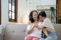 Portrait happy adult daughter and older mother hugging and holding hands, sitting on couch at home, young woman and Royalty Free Stock Photo
