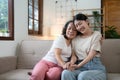 Portrait happy adult daughter and older mother hugging and holding hands, sitting on couch at home, young woman and Royalty Free Stock Photo