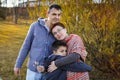 Portrait of happy adult married couple with son at sunset in the park in selective focus