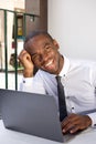 Happy african american business man sitting at table with laptop computer Royalty Free Stock Photo