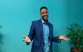 Portrait of happy african american businessman gesturing while standing against blue wall Royalty Free Stock Photo