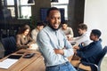 Portrait of happy african american businessman posing with folded arms and smiling at camera, leaning on desk in office Royalty Free Stock Photo