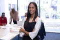 Portrait of happy african american businesswoman with arms crossed against team in boardroom Royalty Free Stock Photo