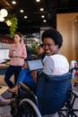 Portrait of happy african american casual businesswomen in wheelchair holding tablet in office Royalty Free Stock Photo