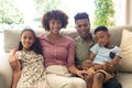 Portrait of happy african american couple with son and daughter sitting on couch at home, smiling Royalty Free Stock Photo