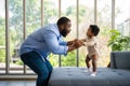 Portrait Of Happy African American Dad With Cute Little Baby Girl on couch at home in the living room, caring father smiling and Royalty Free Stock Photo