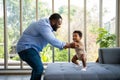 Portrait Of Happy African American Dad With Cute Little Baby Girl on couch at home in the living room, caring father smiling and Royalty Free Stock Photo