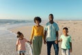 Portrait of happy african american family holding hands while standing at beach against blue sky Royalty Free Stock Photo