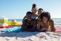 Portrait of happy african american family lying together on towel at beach during sunny day Royalty Free Stock Photo