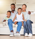 Portrait of a happy african american family with two children sitting on the couch at home. Adorable little girl and boy Royalty Free Stock Photo