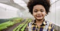 Portrait of happy African American farmer child boy with afro hairstyle standing smiling and looking at camera in greenhouse Royalty Free Stock Photo